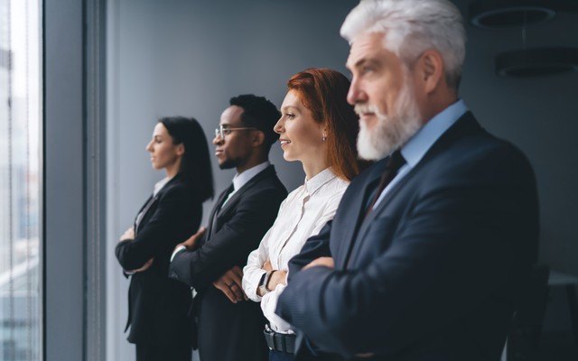 Four leaders standing at a boardroom window, reviewing the work together